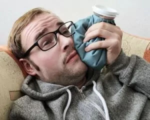 Man with tooth pain ices his sore jaw.