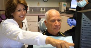 Mechanicsville dentist Dr. McCray showing one of her patients how fixed implant dentures work.