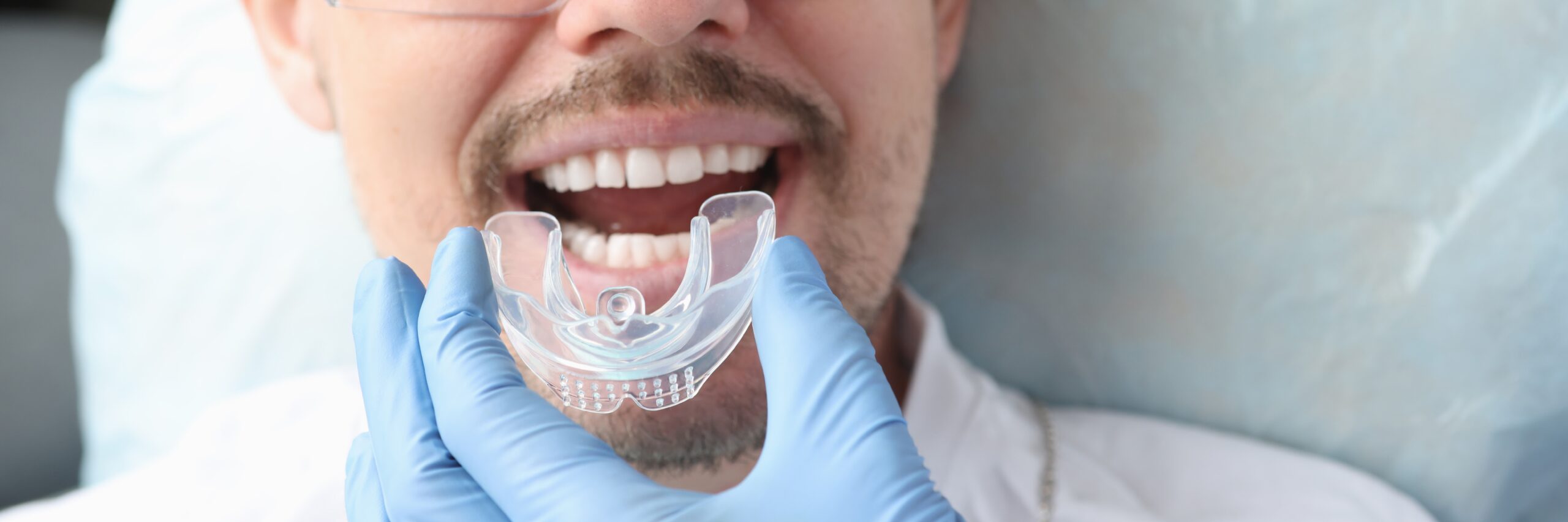 Dentist trying on mouthguard for male patient suffering bruxism
