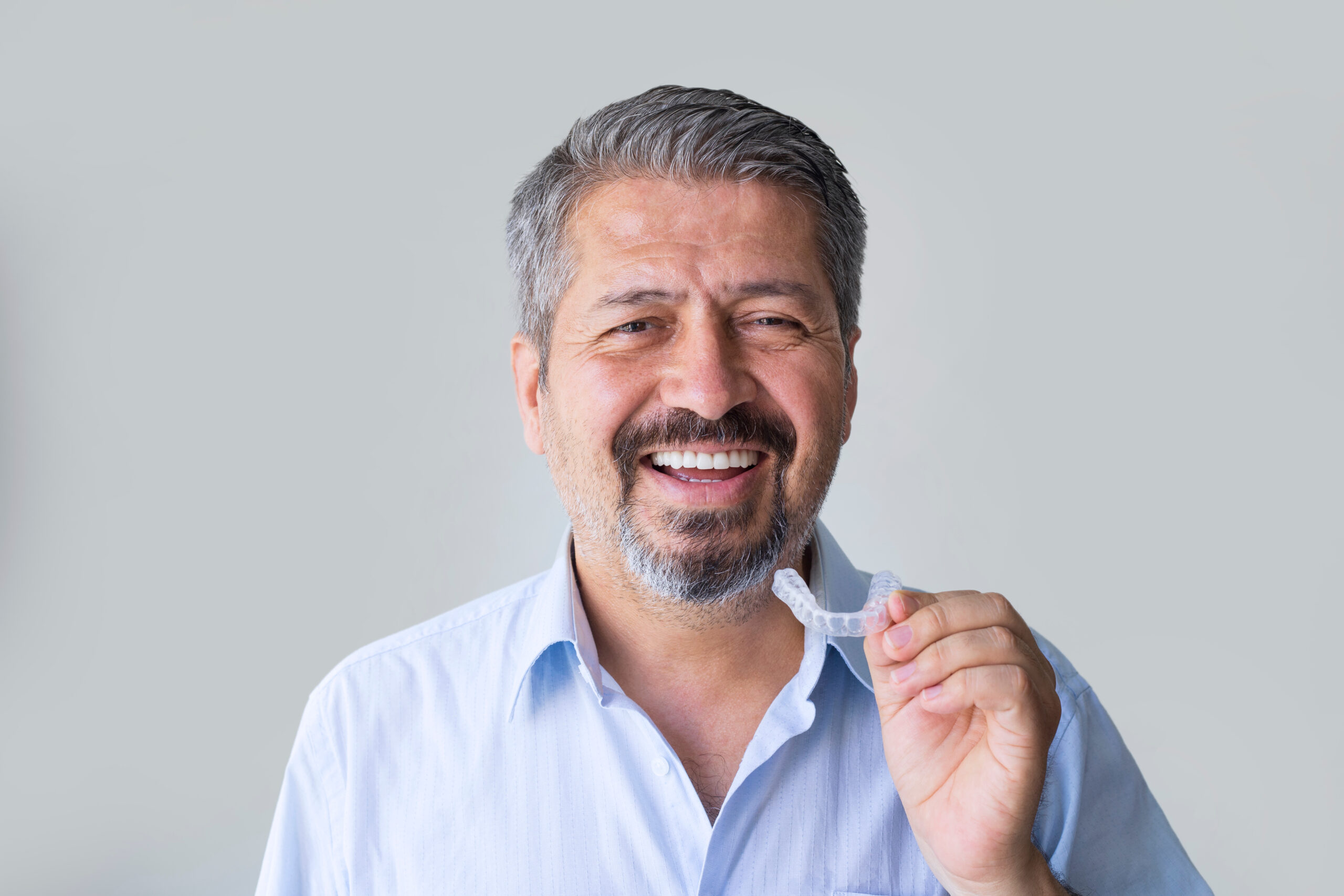 closeup of an older man with clear aligners in hand