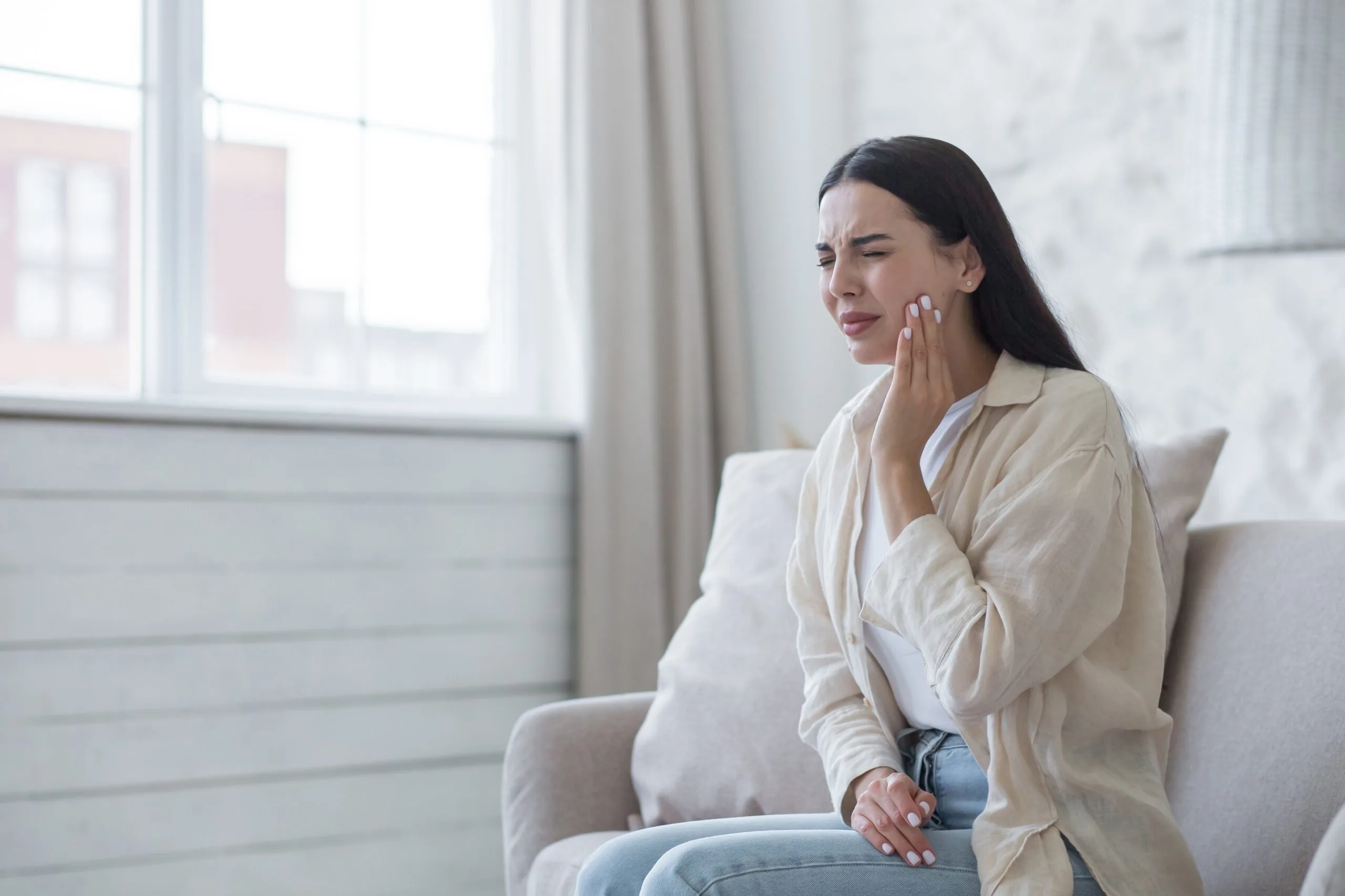 Woman with a toothache clutching her jaw.